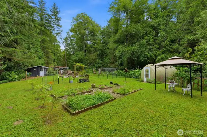 Beautifully established greenhouse surrounded by raised garden beds and organic planting areas. Beautifully established greenhouse surrounded by raised garden beds and organic planting areas.