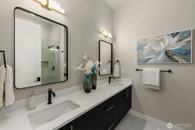 Main floor guest suite bath with dual sinks and framless shower