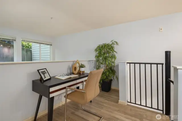 Upper level area perfect for home office, overlooking lower space and framed with windows.