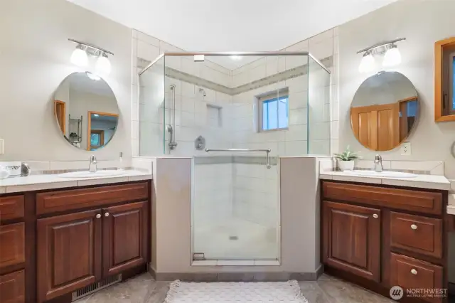 En-suite bathroom with dual vanities, walk-in shower, and radiant tile flooring.