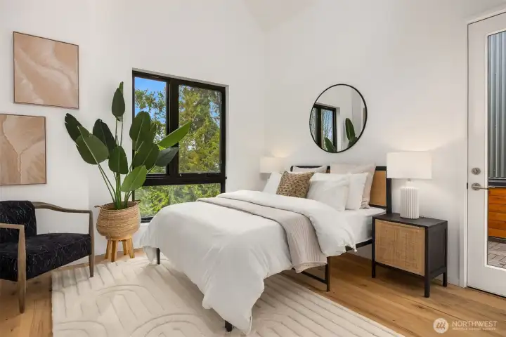 The primary bedroom boasts soaring ceilings, access to the roof deck, large windows, and an abundance of natural light, creating a tranquil and airy retreat within the home.