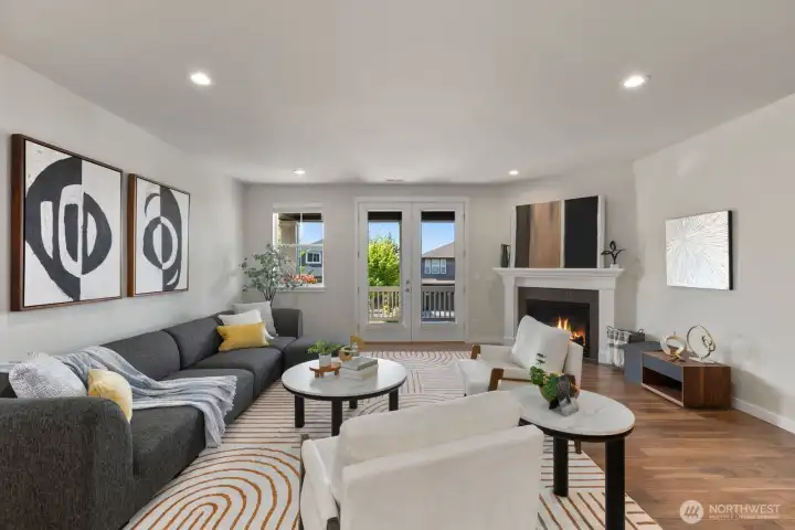 Spacious living room anchored by a cozy fireplace and wired for seamless media integration, with French doors opening to the covered deck, the perfect setting for morning coffee while taking in mountain views.