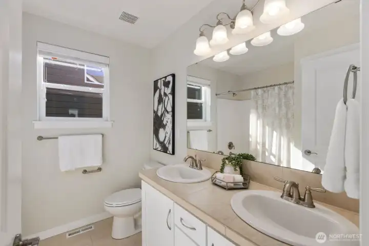 upstairs full bathroom with double sinks, freshly pained cabinets for a light and airy feel, linen closet behind door