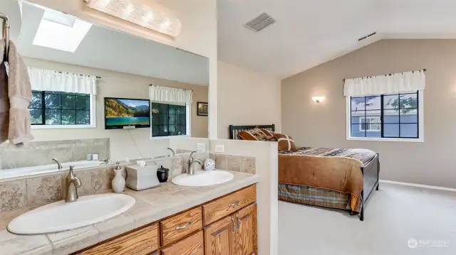 Large vanity with dual sinks and ample storage as well as a skylight that allows an abundance of natural light to beam into this space.