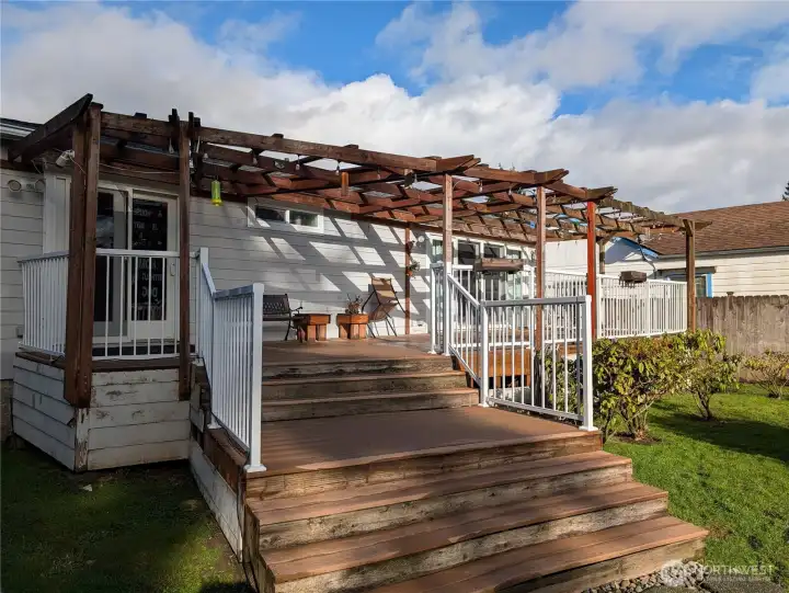 Deck w/ wood pergola over, is the full length of back of house w/ sliders from both bedrooms
