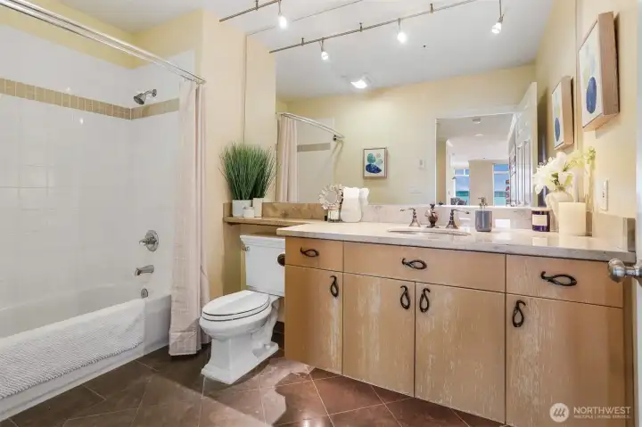 This full bathroom features ceramic tile shower enclosure, natural stone flooring with cozy radiant heat and designer fixtures with an attractive countertop.