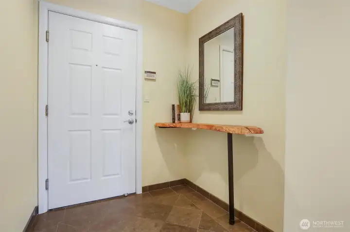 Front entry has stone tile flooring and built in natural wood display shelf.