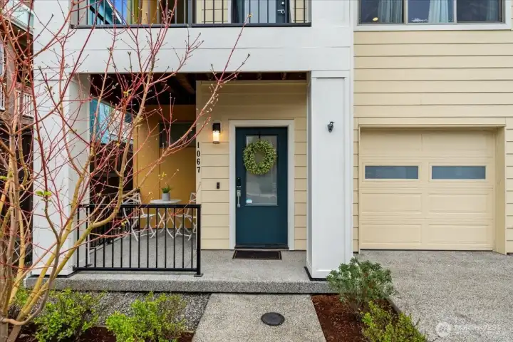 Entryway with covered front porch, seating area, and direct access to the attached garage. Welcoming entry features a defined walkway and landscaped surroundings.