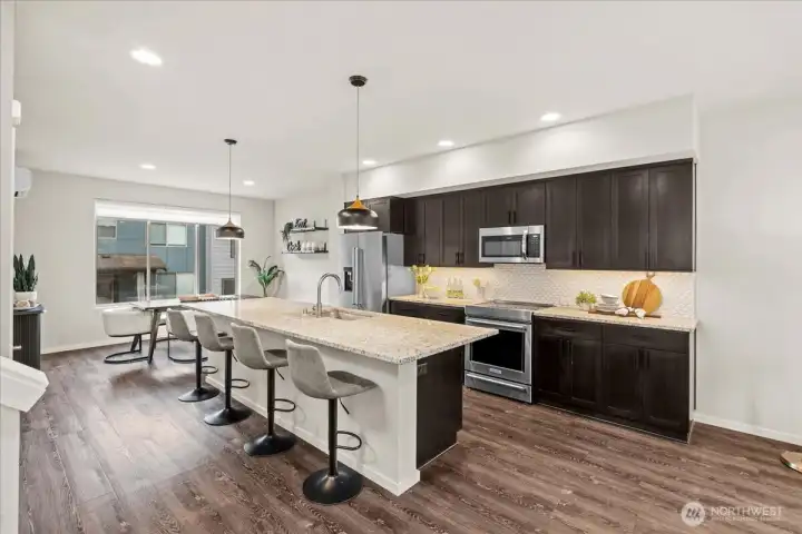 Kitchen featuring a large kitchen island with seating, quartz countertops, and modern cabinetry. Stainless steel appliances and pendant lighting complete the space.