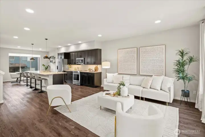 Open-concept living and kitchen area with seamless flow between spaces. Ample lighting and consistent flooring enhance the cohesive layout.