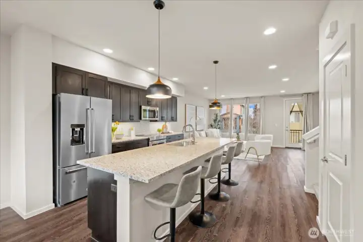 Kitchen alternate view featuring an oversized island with bar seating, stainless steel refrigerator, and ample cabinetry for storage.
