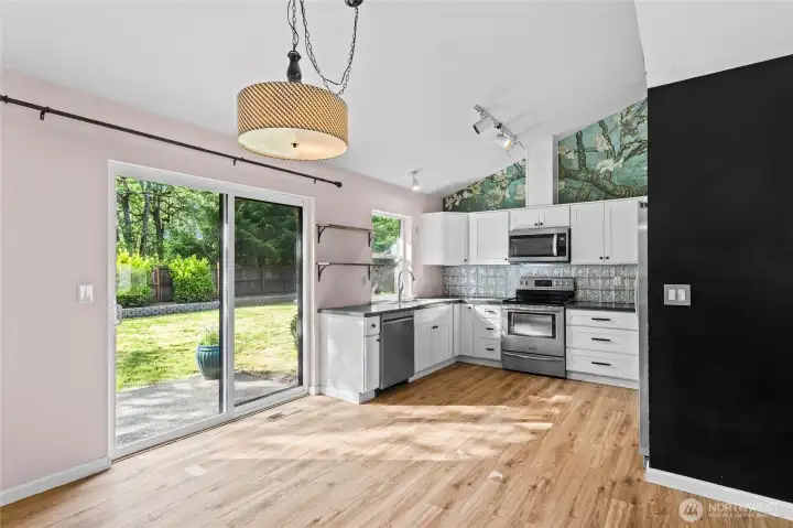 View from dining area looking back towards the Kitchen with all Stainless Appliances that stay.Sliding door leads out to rear patio and huge fully fenced back yard.