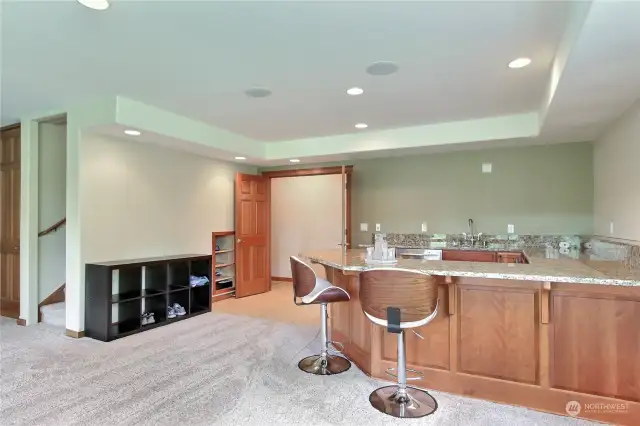 View of wet bar showing stairs to upper main level, custom wood wet bar with solid granite and through those French doors you have another bedroom and bath.