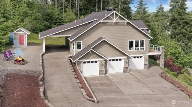 Drone shot of side of home, extremely roomy 3-car garage, plus carport gives you so many options. Well pump house and firepit to your left, most of the landscaping is low maintenance.