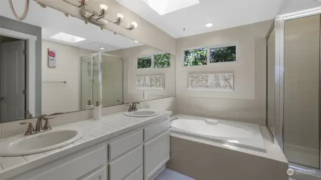Primary bathroom boasts dual sinks, large tub, water closet and skylight.