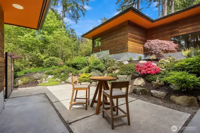 The back patio surrounded by rich, curated gardens.