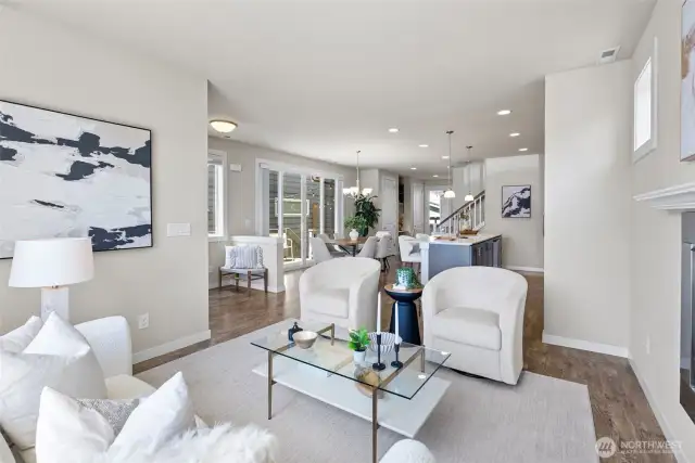 Open-concept main floor featuring laminate wood flooring, recessed lighting, and seamless flow from the bright living room to the large kitchen.