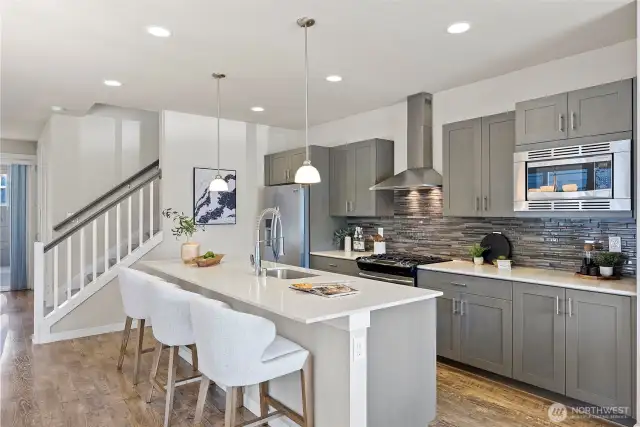 The chef’s kitchen features a gas range, huge quartz island, stainless steel appliances, and quartz countertops!