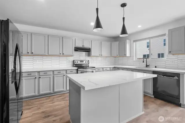 Pendant lighting above the island counter with eating bar in the open concept Kitchen.