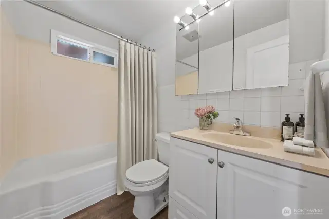 A full bathroom with a tub/shower combo, ample storage, and vanity lighting—ready to serve both family and guests. (Virtually Staged)