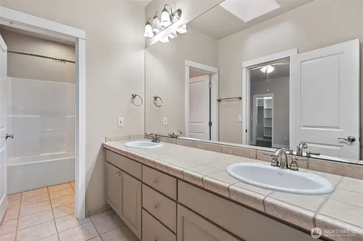 Shared bath for two guest rooms with separate access doors, two basins, separate shower, and toilet area. Perfect for morning routines!