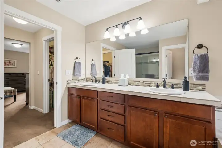 The ensuite bath features a tile shower and dual vanities, blending luxury with function. Thoughtful design enhances both comfort and style.