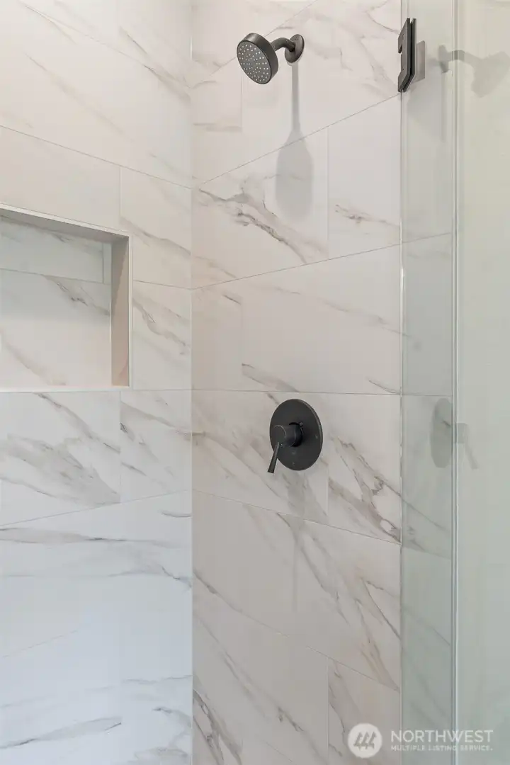 Shower has floor to ceiling porcelain tile.