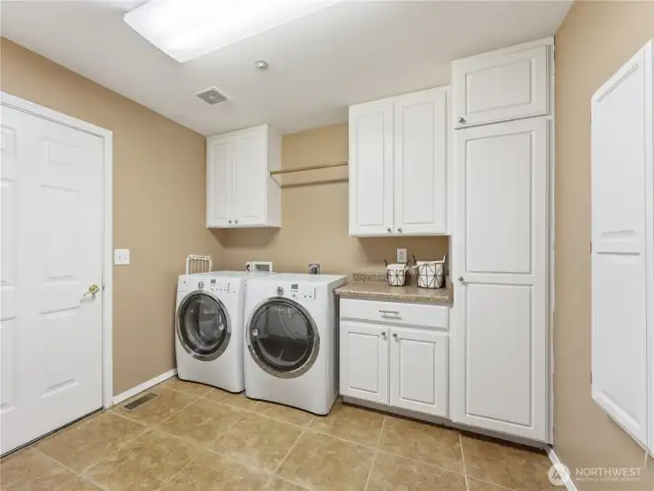 Spacious laundry room with extra storage conveniently located near the garage entry.