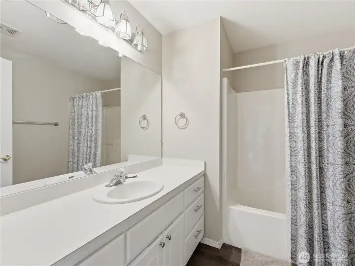 Full bathroom featuring tub surround and convenient access to secondary bedrooms