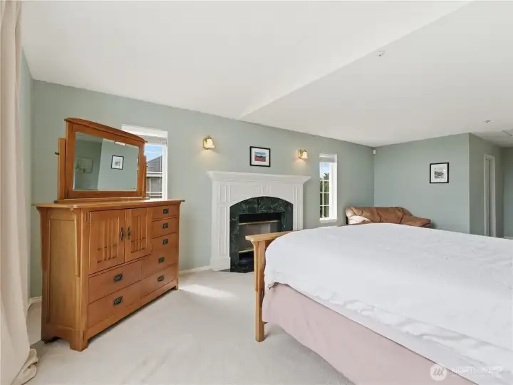 Spacious primary bedroom retreat featuring a cozy wood-burning fireplace.