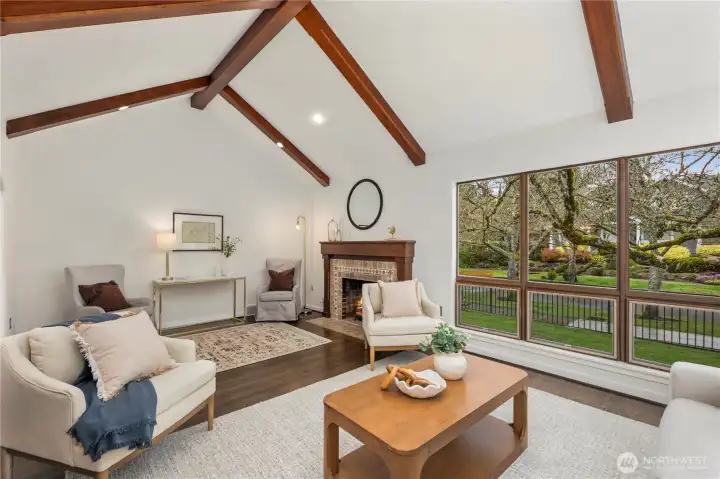 The living room impresses with soaring vaulted ceilings, exposed wood beams, and expansive picture windows that fill the space with natural light.