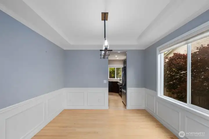 Dedicated dining space with detailed millwork, crown molding, and a large window that brings in natural light. Dedicated dining space with detailed millwork, crown molding, and a large window that brings in natural light.