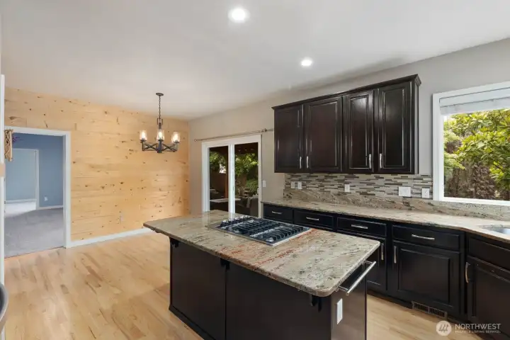 The kitchen features extensive cabinet storage, an oversized island, and a gas cooktop at the center of the workspace. The kitchen features extensive cabinet storage, an oversized island, and a gas cooktop at the center of the workspace.