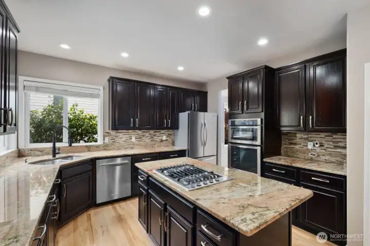 Dark cabinetry, abundant storage, and a central island create a kitchen built for gathering and meal preparation. Dark cabinetry, abundant storage, and a central island create a kitchen built for gathering and meal preparation.