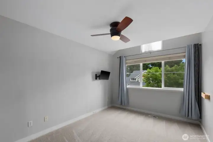 Bedroom with vaulted ceilings, soft natural light, and a large window overlooking the neighborhood. Neutral finishes and a ceiling fan add comfort and flexibility. Bedroom with vaulted ceilings, soft natural light, and a large window overlooking the neighborhood. Neutral finishes and a ceiling fan add comfort and flexibility.