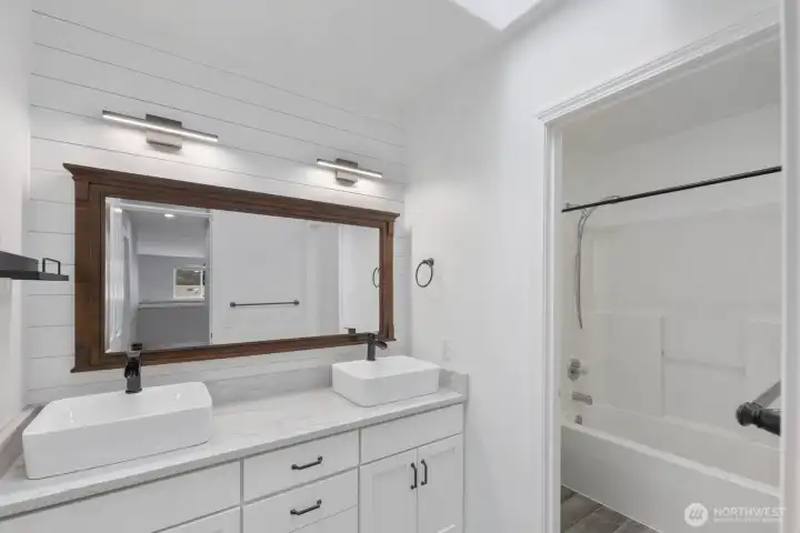 Bathroom with dual vessel sinks, expansive mirror, and a tub/shower combination. Bright finishes and thoughtful details create a clean, modern feel. Bathroom with dual vessel sinks, expansive mirror, and a tub/shower combination. Bright finishes and thoughtful details create a clean, modern feel.