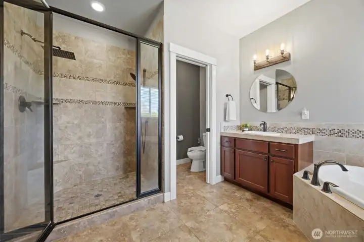 Tiled walk in shower and commode room in the primary en-suite