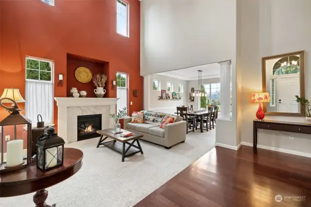 Living room with gas fireplace, vaulted ceiling, accent wall, view toward dining room