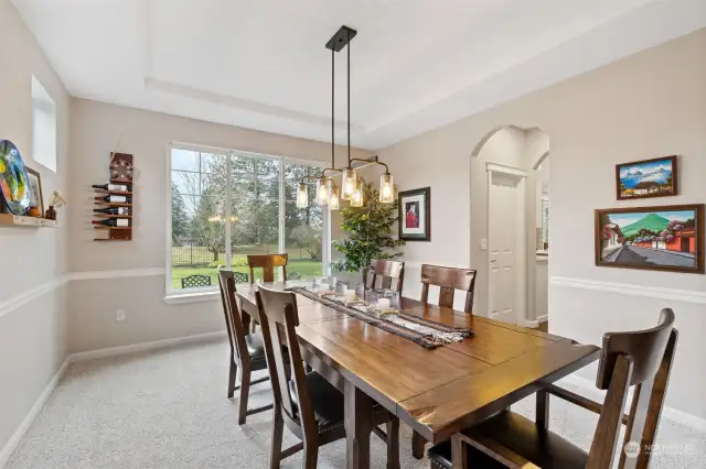 Formal dining room with view toward patios and yard. Doorway on right provides access to walk-in pantry and kitchen.