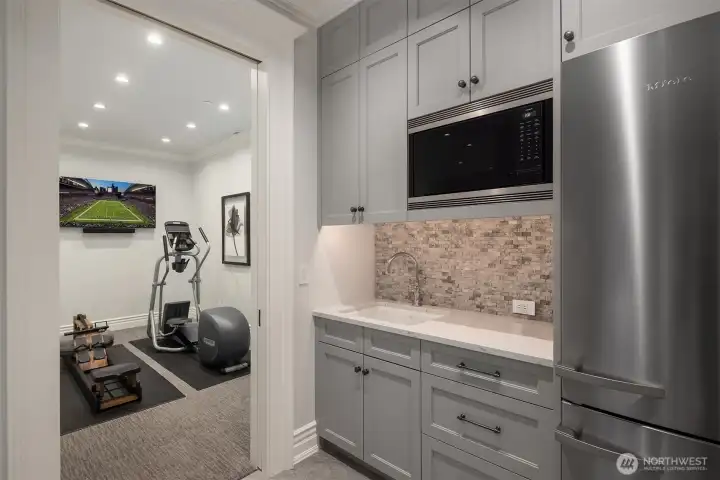 Lower level exercise suite with adjacent bistro kitchen.