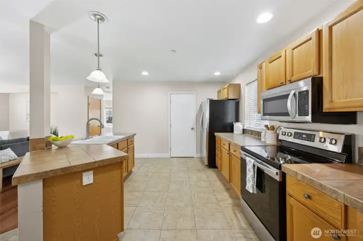 Spacious kitchen with a walk in pantry beside fridge.