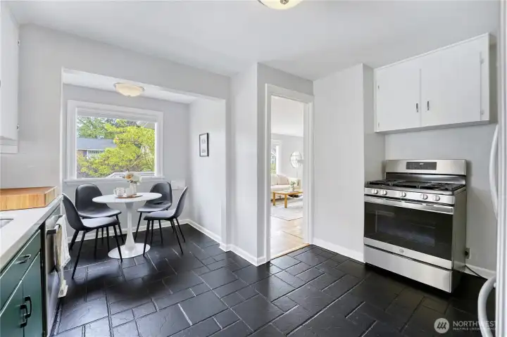 A modern kitchen with stainless steel appliances, an eating nook, and quartz