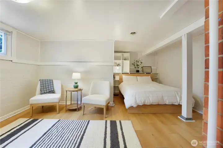 Enormous lower level bedroom with sitting area has high ceilings.