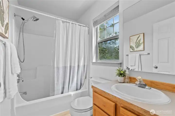 Full primary bathroom with a tub/shower combination, window for natural light, and convenient access from the hallway.