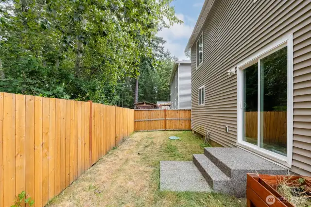 Low-maintenance backyard includes a concrete patio and grassy area—perfect for outdoor relaxation or entertaining.