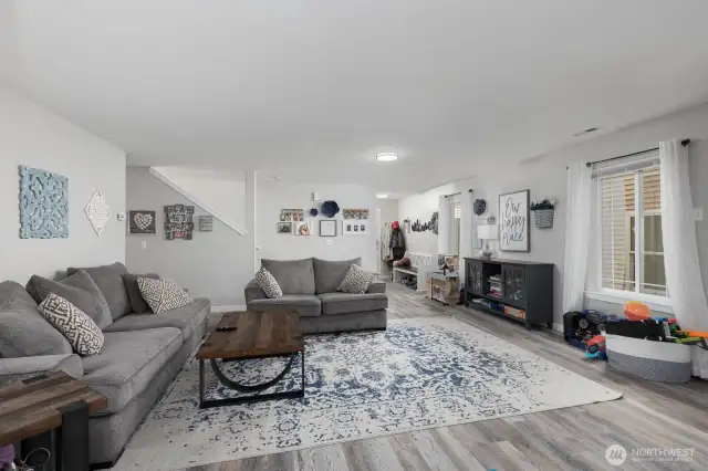 The spacious living room is designed for comfort, featuring large windows, warm finishes, and plenty of space for relaxing or entertaining guests.