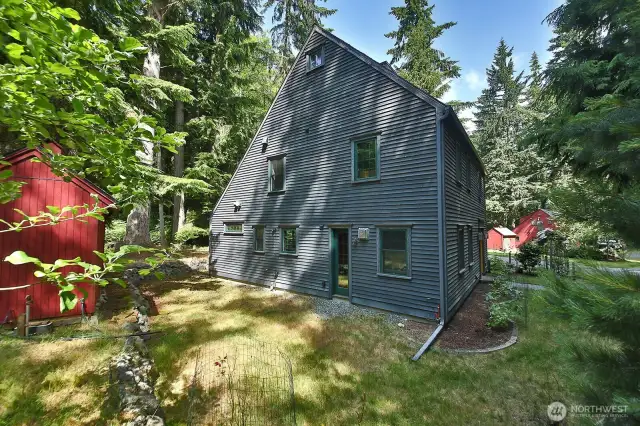This is the southern side of the home. House siding is 4" Reveal Clapboard Cedar. Small red shed contains a spin down filter for the incoming water from the community well.