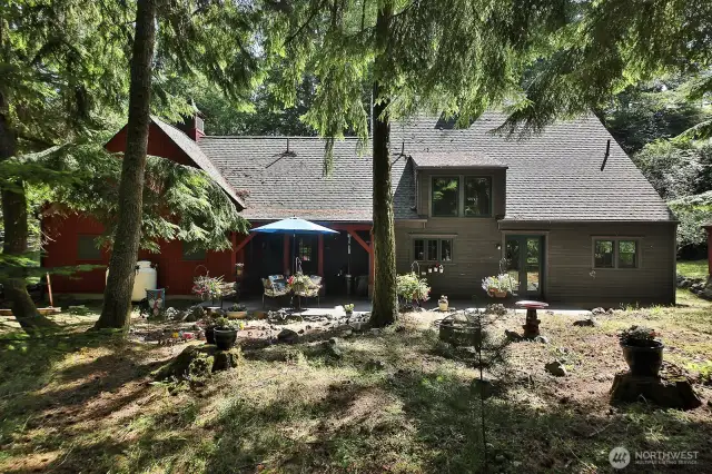 West/backside of home. Trails from the house lead to over 100 acres of trust lands with trails. Cedar deck with covered area connected to the kitchen. You are close to nature, wildlife and the sweet village of Langley.