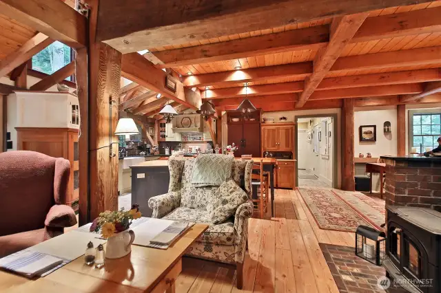 Main level floor of the house has a layer of 3/4 inch of plywood under 3/4 inch tongue and groove Douglas Fir milled on site from extra timbers. Straight ahead, through the opening is the entry way. Your back is to the Primary Suite. The Vermont Castings wood stove is seen in the right lower corner of this photo.