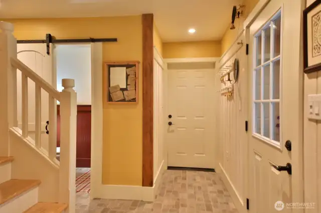 Back in the entryway. Half bath is beyond the barn door to the left. Garage is straight ahead. Let's go check out the half bath and then head upstairs.